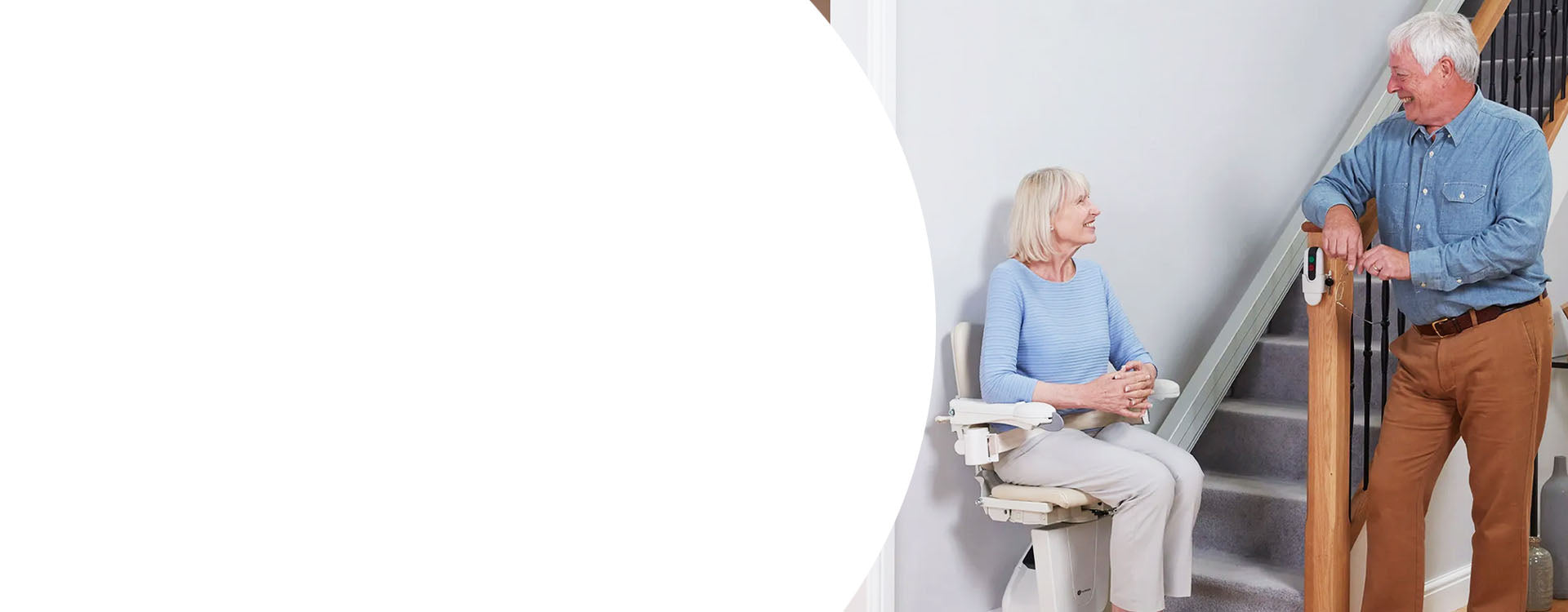 Two elderly people using a stairlift on a staircase.